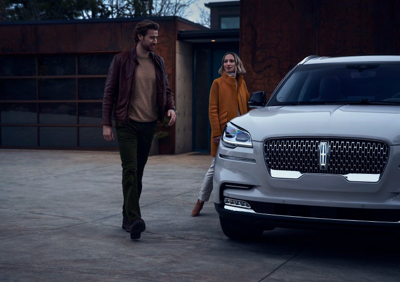 A man and a woman approaching a 2024 Lincoln Aviator® SUV, which illuminates certain lights when they are close | Stivers Lincoln (AL) in Montgomery AL