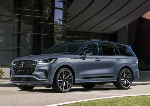 A gray 2025 Lincoln Aviator® SUV is parked outside a modern building showcasing the driver’s side of the vehicle. | Stivers Lincoln (AL) in Montgomery AL