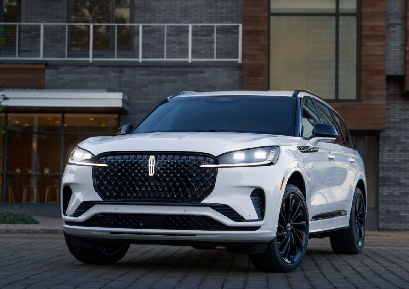 A 2026 Lincoln Aviator® Reserve model is shown with the available Jet Appearance Package parked near a restaurant. | Stivers Lincoln (AL) in Montgomery AL