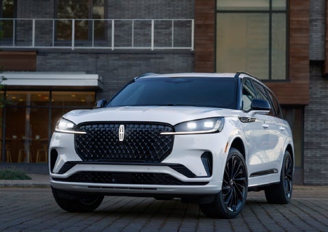 A 2026 Lincoln Aviator® Reserve model is shown with the available Jet Appearance Package parked near a restaurant. | Stivers Lincoln (AL) in Montgomery AL