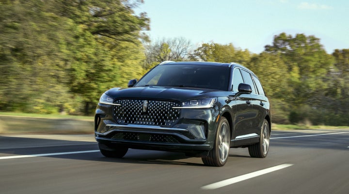 A 2026 Lincoln Black Label™ Aviator® SUV is being driven down a road lined with trees. | Stivers Lincoln (AL) in Montgomery AL