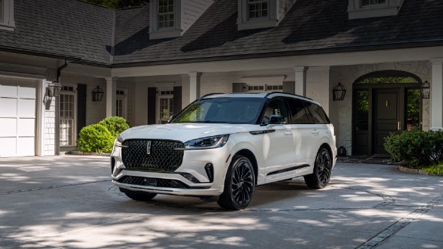 A white 2026 Lincoln Aviator® SUV is parked in the driveway of a luxury home. | Stivers Lincoln (AL) in Montgomery AL