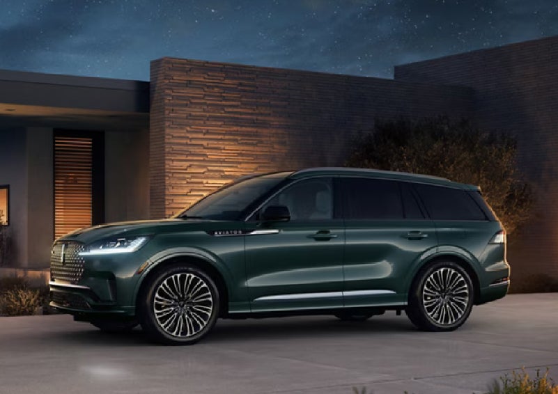 A green 2027 Lincoln Aviator® SUV is parked outside a contemporary home. | Stivers Lincoln (AL) in Montgomery AL