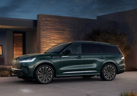 A green 2027 Lincoln Aviator® SUV is parked outside a contemporary home. | Stivers Lincoln (AL) in Montgomery AL