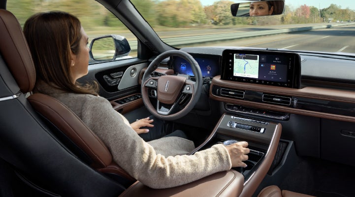 A 2027 Lincoln Aviator® SUV is being driven hands-free on a highway lined with trees. | Stivers Lincoln (AL) in Montgomery AL