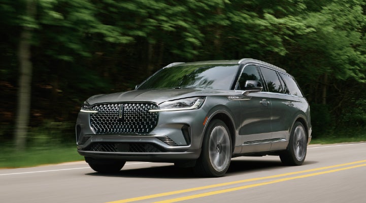 A 2027 Lincoln Aviator® SUV is being driven down a road lined with trees. | Stivers Lincoln (AL) in Montgomery AL
