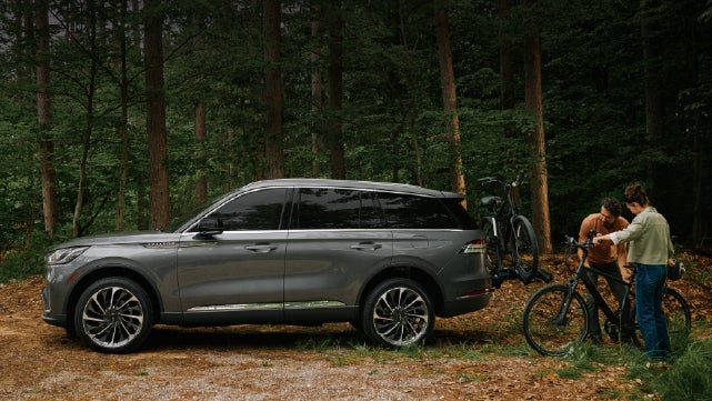 A father and son load e-bikes on a bike rack attached to a 2027 Lincoln Aviator® SUV. | Stivers Lincoln (AL) in Montgomery AL