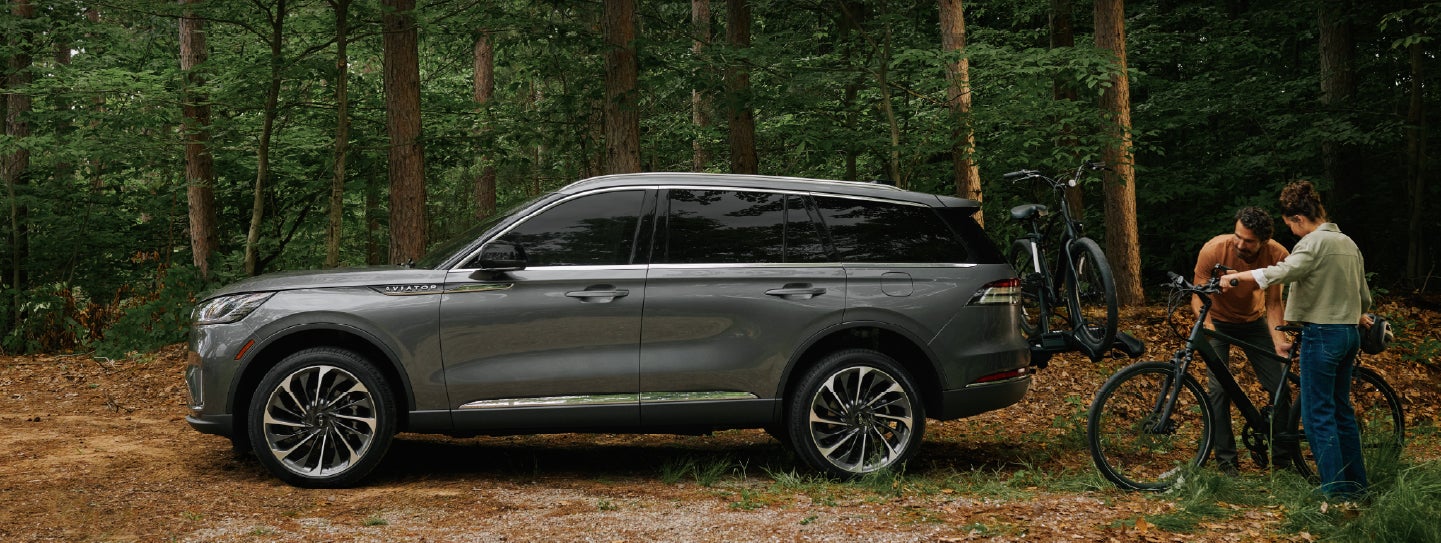 A father and son load e-bikes on a bike rack attached to a 2027 Lincoln Aviator® SUV. | Stivers Lincoln (AL) in Montgomery AL